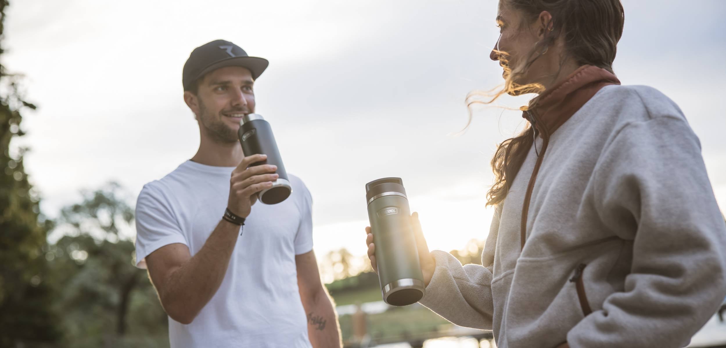 Thermosflaschen Frau und Mann im Sonnenuntergang im Park